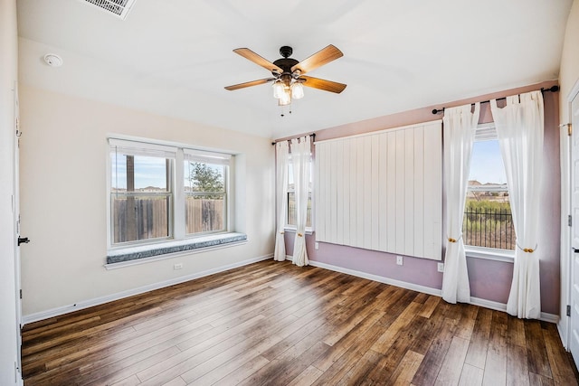 unfurnished room featuring a healthy amount of sunlight, dark wood-type flooring, and ceiling fan