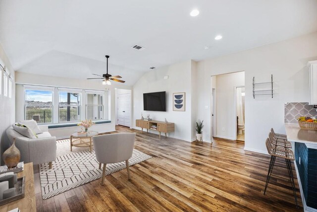 living room featuring ceiling fan, wood-type flooring, and vaulted ceiling