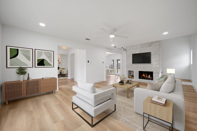 living room with ceiling fan, light hardwood / wood-style flooring, and a fireplace