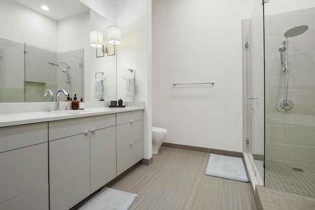 bathroom featuring a shower with shower door, vanity, and toilet