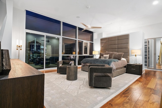 bedroom with ceiling fan, expansive windows, and light hardwood / wood-style floors