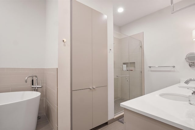 bathroom featuring independent shower and bath, tile walls, and vanity