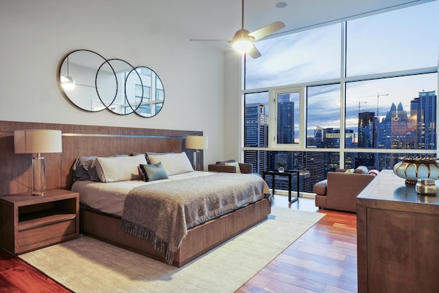 bedroom featuring ceiling fan, a wall of windows, and light hardwood / wood-style floors