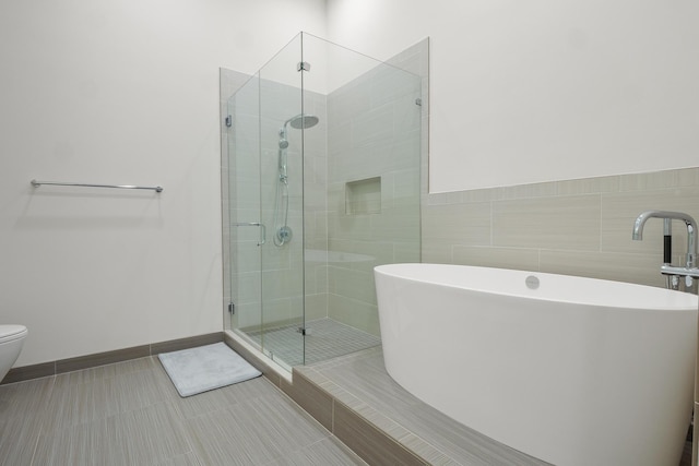 bathroom with toilet, tile patterned flooring, and shower with separate bathtub