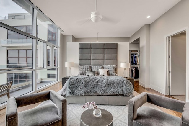 bedroom featuring ceiling fan, a walk in closet, wood-type flooring, and a closet