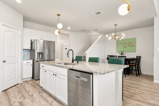 kitchen featuring appliances with stainless steel finishes, an island with sink, and white cabinets