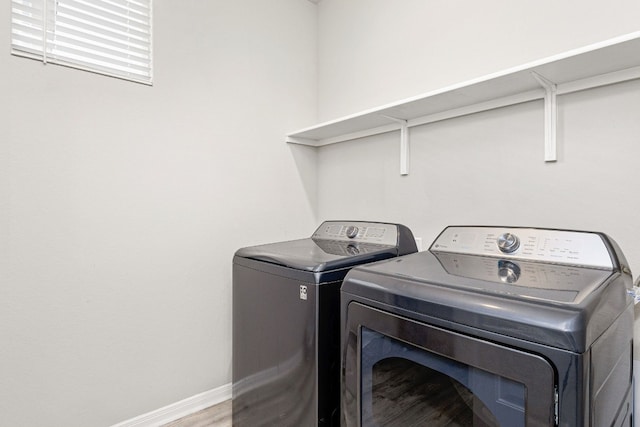 clothes washing area with hardwood / wood-style floors and washer and clothes dryer