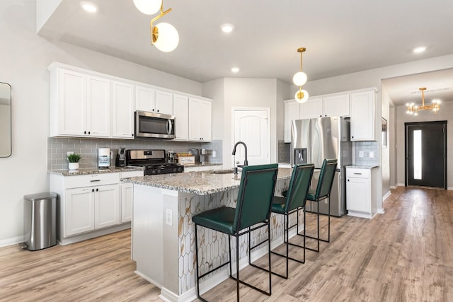 kitchen with appliances with stainless steel finishes, sink, hanging light fixtures, and white cabinets