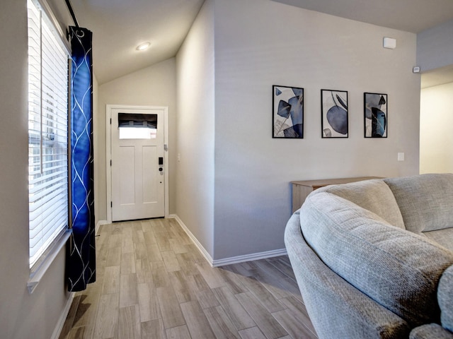 entrance foyer with a healthy amount of sunlight, vaulted ceiling, and light hardwood / wood-style flooring