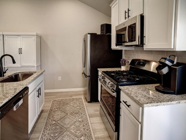 116 Shagbark Dr, Bastrop, TX 78602 - kitchen featuring appliances with stainless steel finishes, a sink, tasteful backsplash, white cabinetry, and lofted ceiling
