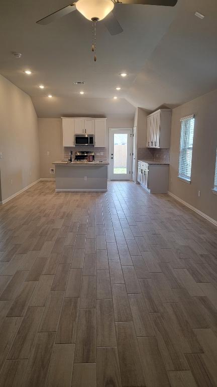 116 Shagbark Trl, Bastrop, TX 78602 - kitchen with appliances with stainless steel finishes, open floor plan, a ceiling fan, decorative backsplash, and vaulted ceiling