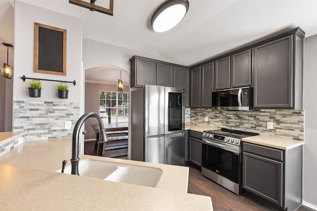 kitchen with tasteful backsplash, pendant lighting, sink, stainless steel appliances, and dark hardwood / wood-style flooring