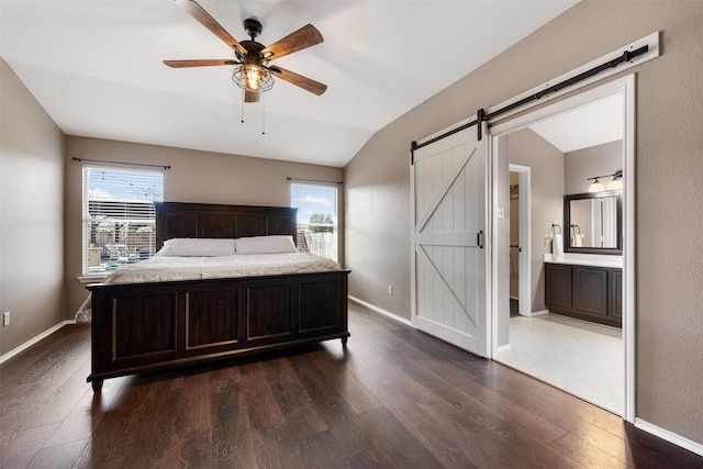 bedroom featuring a barn door, ceiling fan, connected bathroom, vaulted ceiling, and multiple windows