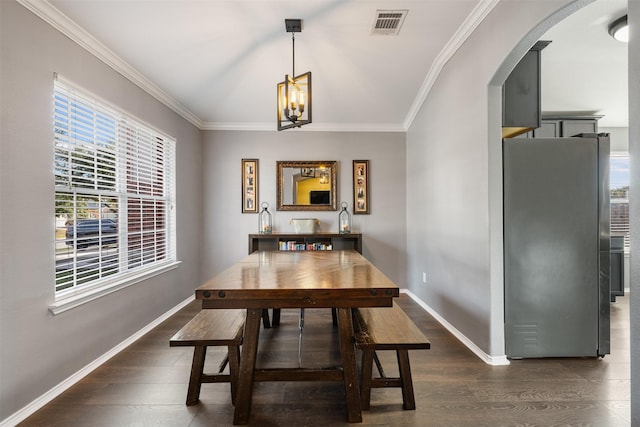 dining space featuring dark wood-type flooring, crown molding, and a notable chandelier