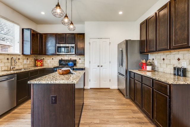 kitchen with a kitchen island, appliances with stainless steel finishes, decorative light fixtures, sink, and dark brown cabinets