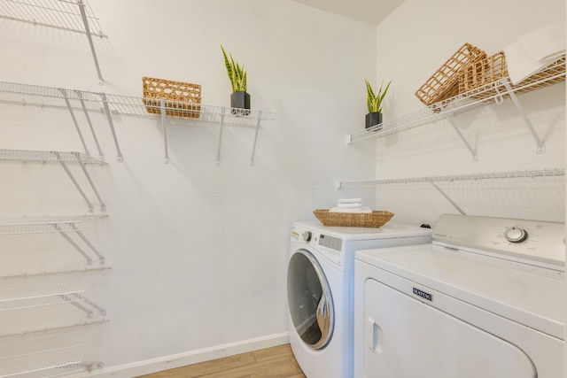 laundry room featuring separate washer and dryer and light hardwood / wood-style flooring