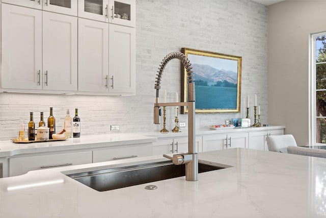 kitchen featuring decorative backsplash, sink, and white cabinetry