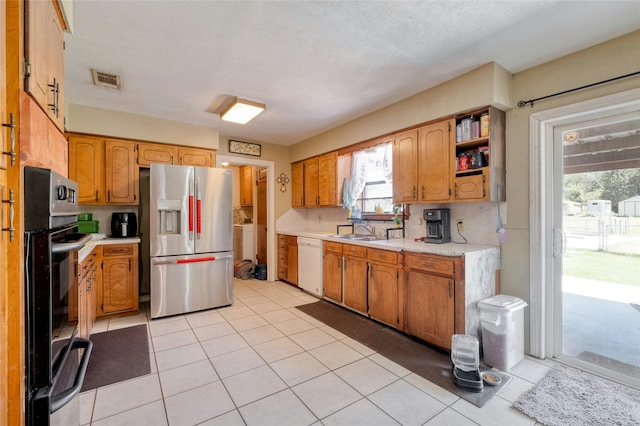 kitchen featuring stainless steel fridge with ice dispenser, a healthy amount of sunlight, white dishwasher, and sink