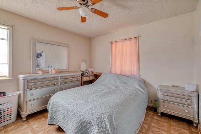 bedroom with a textured ceiling, ceiling fan, light parquet flooring, and multiple windows