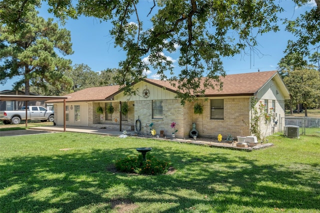 ranch-style house featuring a front lawn, cooling unit, and a carport