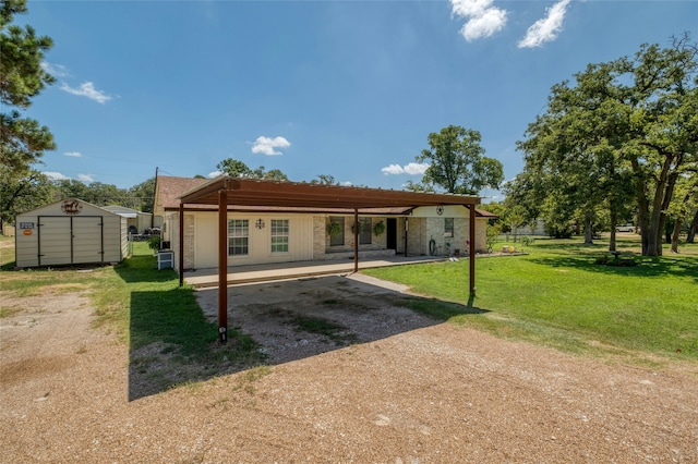 back of house featuring a carport, a lawn, and a storage unit