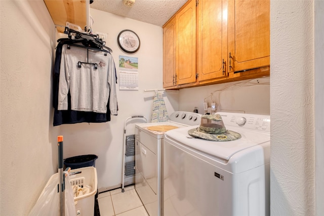 laundry room with cabinets, separate washer and dryer, light tile patterned floors, and a textured ceiling