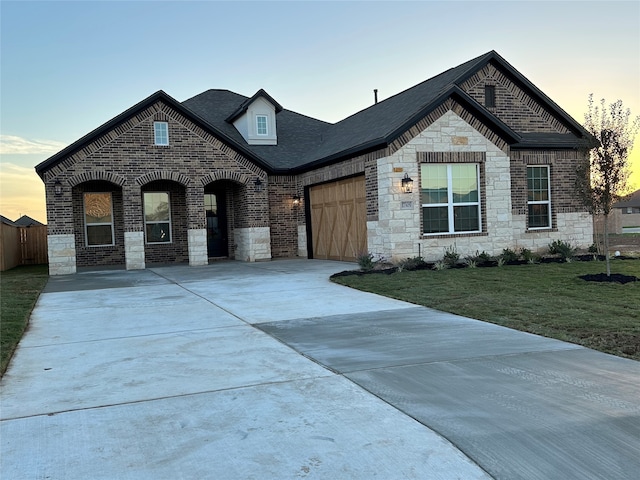 french country inspired facade featuring a yard and a garage