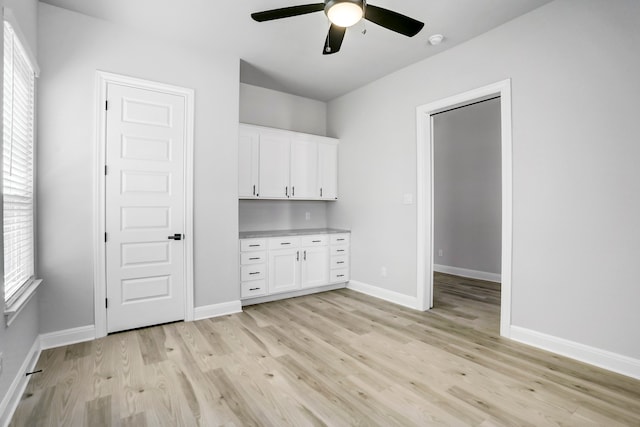 interior space with ceiling fan, plenty of natural light, white cabinetry, and light hardwood / wood-style floors