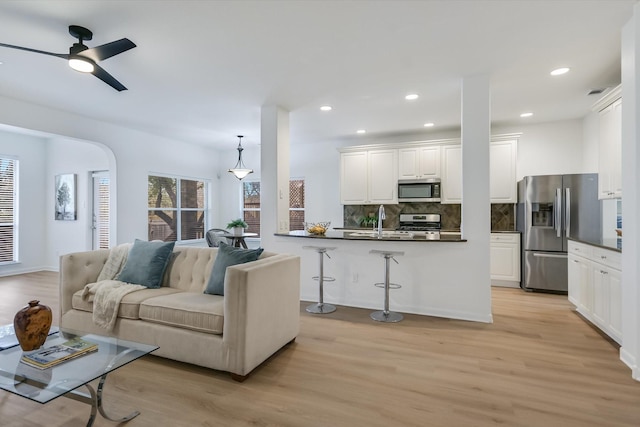 living room with ceiling fan, sink, and light hardwood / wood-style flooring