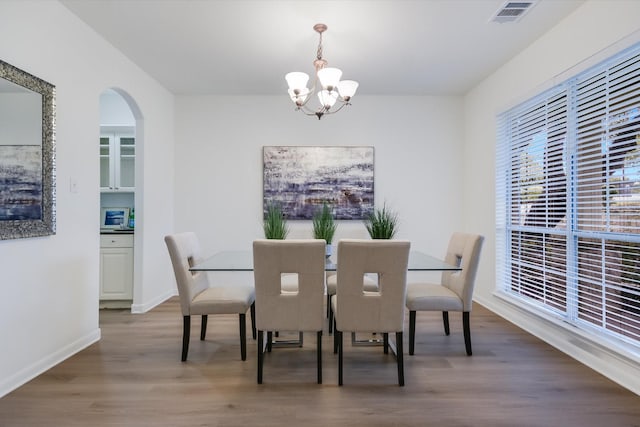 dining space featuring wood-type flooring and an inviting chandelier