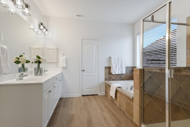 bathroom featuring independent shower and bath, wood-type flooring, and vanity