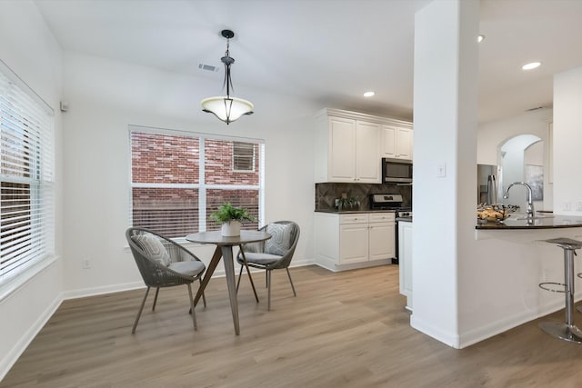 dining space featuring light wood-type flooring, plenty of natural light, and sink