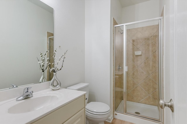 bathroom featuring toilet, vanity, and a shower with shower door