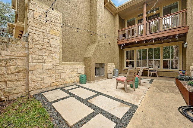 view of patio with an outdoor fireplace and a balcony