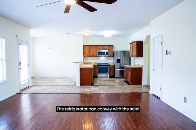 kitchen with stainless steel appliances, light hardwood / wood-style floors, sink, hanging light fixtures, and ceiling fan