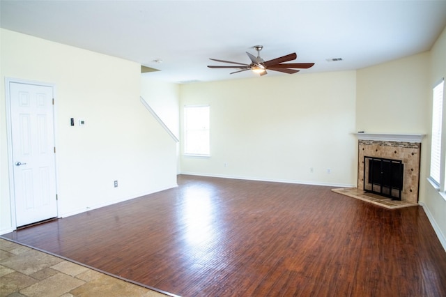 unfurnished living room featuring ceiling fan and a tile fireplace