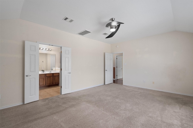 unfurnished bedroom with ceiling fan, light colored carpet, ensuite bathroom, and vaulted ceiling