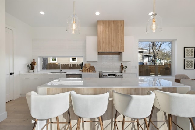 kitchen with decorative light fixtures, white cabinetry, stove, and a kitchen island