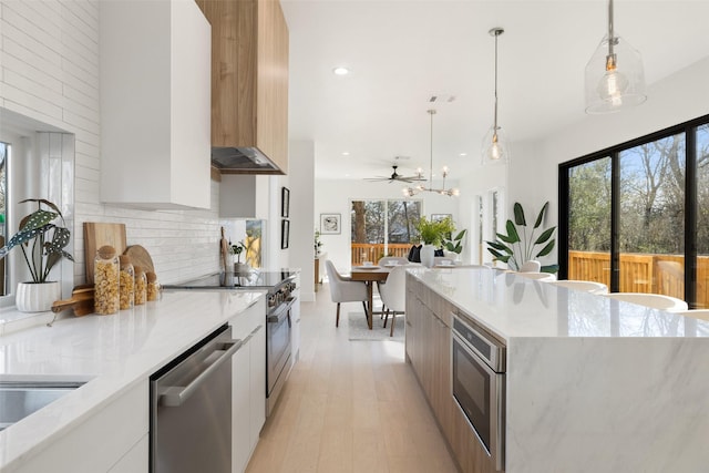 kitchen with decorative light fixtures, white cabinetry, stainless steel appliances, tasteful backsplash, and ceiling fan