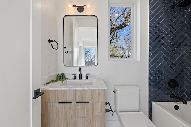 full bathroom featuring tiled shower / bath combo, vanity, and toilet