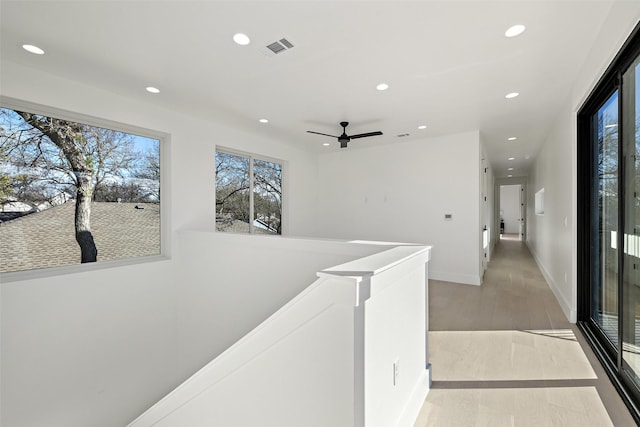 hallway with light wood-type flooring and a wealth of natural light