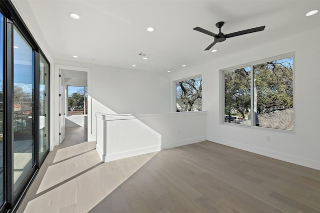 unfurnished room with ceiling fan, wood-type flooring, and a healthy amount of sunlight