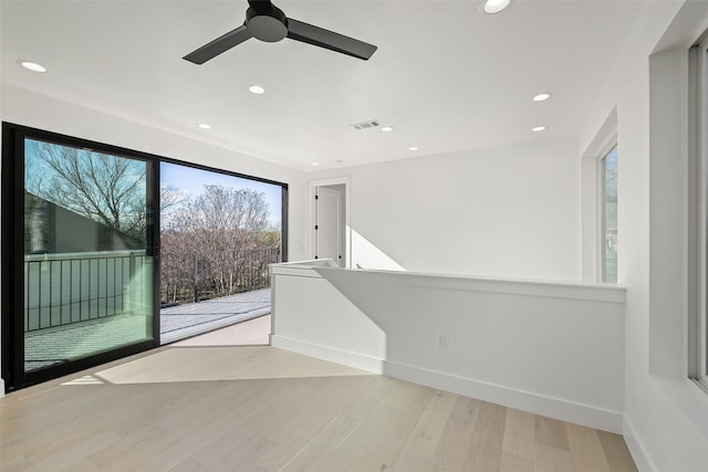 empty room with ceiling fan, plenty of natural light, and light hardwood / wood-style floors