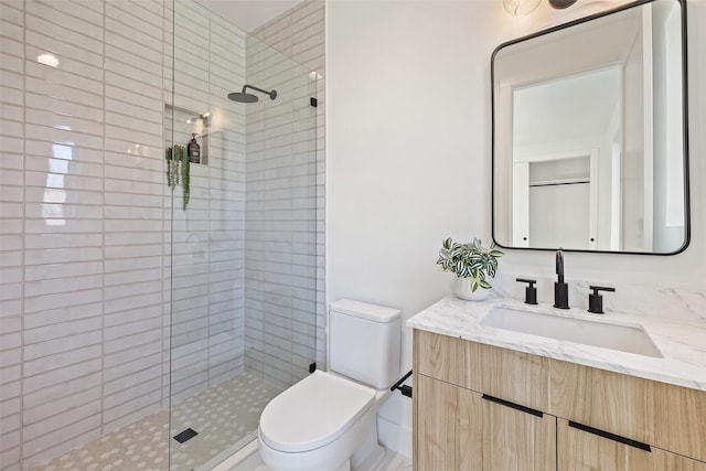 bathroom with toilet, vanity, and a shower with door