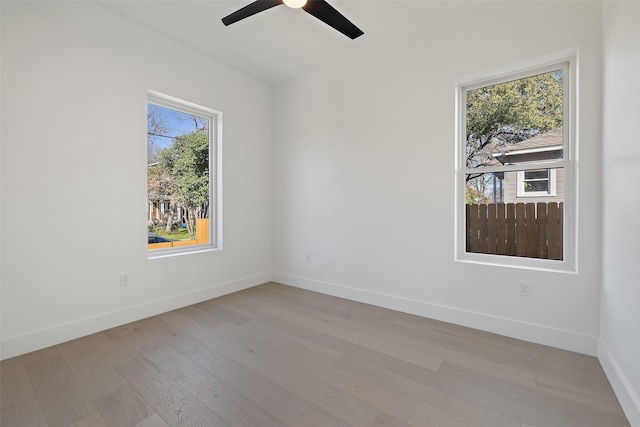 spare room featuring ceiling fan, light wood-type flooring, and a wealth of natural light