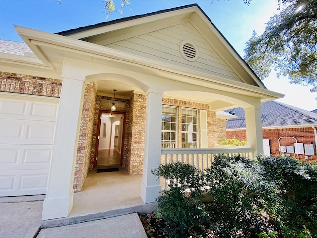 doorway to property with a garage and covered porch