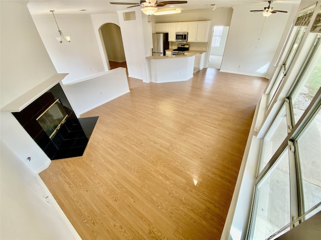 unfurnished living room featuring ceiling fan, a fireplace, and light hardwood / wood-style floors