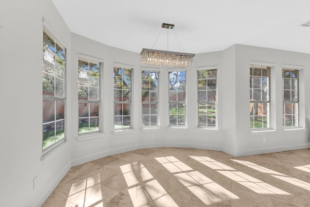 unfurnished sunroom featuring plenty of natural light and an inviting chandelier