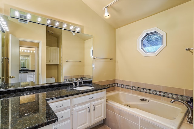 full bath with a garden tub, toilet, track lighting, lofted ceiling, and vanity