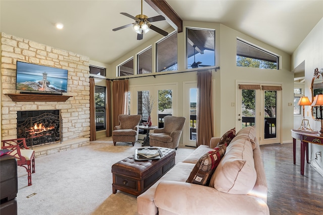 living room featuring a stone fireplace, beam ceiling, plenty of natural light, and french doors